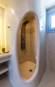 a bathroom with a shower with a round mirror at Plaka Suites in Plaka Milou