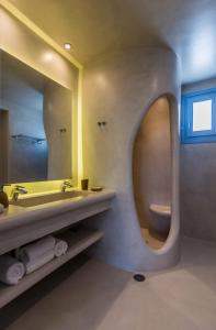 a bathroom with a round mirror and a sink at Plaka Suites in Plaka Milou