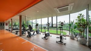Apartment The Base Bukit Phuket في فوكيت تاون: صالة ألعاب رياضية مع أجهزة المشي وأجهزة بيضاوية