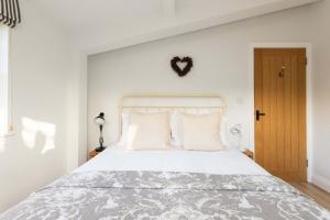 a bedroom with a large white bed with white pillows at Sidlesham Hideaway Logburner & Garden in Donnington