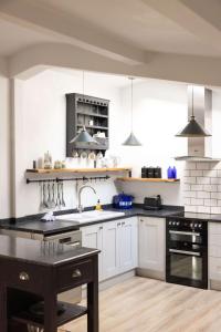 a kitchen with white cabinets and black appliances at Sidlesham Hideaway Logburner & Garden in Donnington