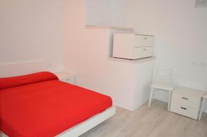 a white bedroom with a red bed and a chair at Casa Leone 1 in Caorle