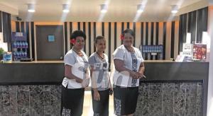 drei Personen stehen vor einer Theke in einem Geschäft in der Unterkunft Peninsula International Hotel in The Domain