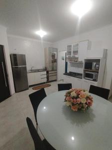 eine Küche und ein Esszimmer mit einem Tisch mit Blumen darauf in der Unterkunft Casa c ar condicionado à 600m mar in Itapoa
