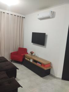 ein Wohnzimmer mit einem TV und einem roten Stuhl in der Unterkunft Casa c ar condicionado à 600m mar in Itapoa + 3 Fotos