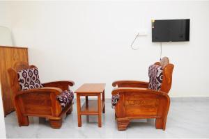 three chairs and a table in a room with a tv at Kitty Royal Inn in Ooty