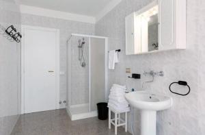 un bagno bianco con lavandino e doccia di La Terrazza Guest House a San Zeno Altre 7 foto