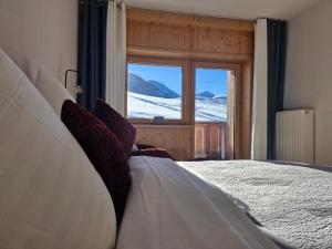 ein Schlafzimmer mit einem Bett und Blick auf den Schnee in der Unterkunft Neunerköpfle in Tannheim