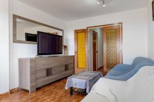 ein Wohnzimmer mit einem TV auf einer Kommode mit einem Bett in der Unterkunft Apartamento Segur Calafell in Calafell