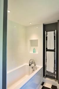 een witte badkamer met een bad en een wastafel bij Finest Retreats - Meadowsweet Cottage in Wingfield +12 foto's