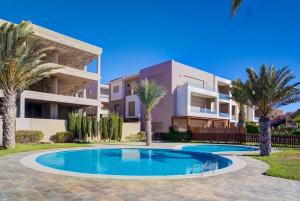 a villa with a swimming pool and palm trees at Charming Seaside Apartment with Pool & Direct Beach Access in Agadir nʼ Aït Sa