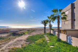 a house on the beach with palm trees at Charming Seaside Apartment with Pool & Direct Beach Access in Agadir nʼ Aït Sa