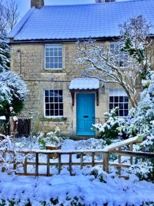 een huis met een blauwe deur in de sneeuw bij Finest Retreats - Flittermouse Cottage in Wingfield