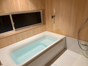 白马村The Guest House Japan Hakuba的带浴缸的浴室,配有电视 更多166张照片