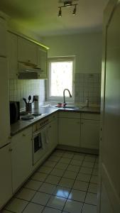 een keuken met witte kasten, een gootsteen en een raam bij Süder11 - ApartB in Eddelak