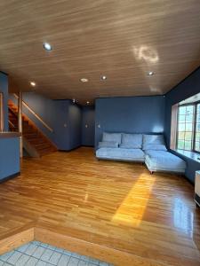 a living room with a blue couch and a wooden floor at Nozawa Nest in Nozawa Onsen