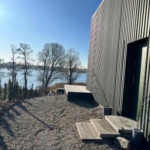 ein Gebäude mit einer Bank neben einem Gewässer in der Unterkunft SEN TOPOLI Domy nad jeziorem 