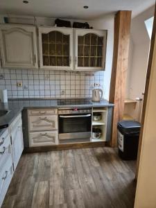 een keuken met witte kasten en een kookplaat oven bij Süder11 - ApartD in Eddelak