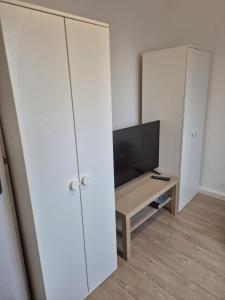 een woonkamer met een witte kast en een televisie bij Süder11 - ApartD in Eddelak +3 foto's