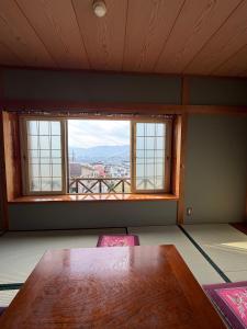 a room with a table and a large window at Nozawa Nest in Nozawa Onsen