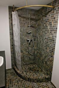 a shower in a tiled bathroom with a shower curtain at Amber White apartment in Juodkrantė