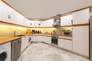 een keuken met witte kasten en een wasmachine en droger bij Superb Large Apartment on the Beach in Marbella