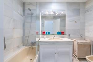 een badkamer met een wastafel, een bad en een spiegel bij Superb Large Apartment on the Beach in Marbella +16 foto's