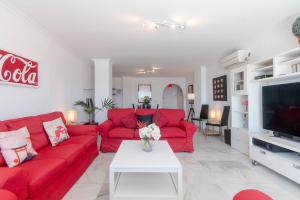 een woonkamer met rode banken en een tv bij Superb Large Apartment on the Beach in Marbella