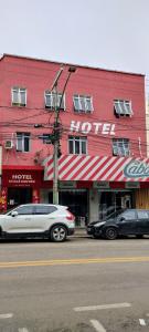 un edificio rosso con auto parcheggiate di fronte di Hotel Chalé Centro a Curvelo