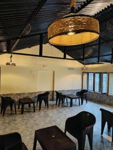 een grote kamer met tafels en stoelen en een kroonluchter bij the jungle book - luxury camps by lake & woods in Bhīm Tāl
