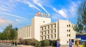 a large white building with a sign on top of it at Jinjiang Inn Harbin Qunli Metro Supermarket Airport Bus Station in Harbin