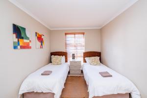 twee bedden in een kamer met witte muren bij The Pelican in Langebaan