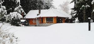 una casa cubierta de nieve delante en Las Bahías en Villa La Angostura