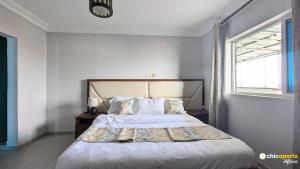 ein Schlafzimmer mit einem großen Bett mit einem großen Fenster in der Unterkunft Chic studio with parking and pool in Douala + 6 Fotos