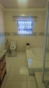 Un baño con bañera, inodoro y ventana. en kiddy, en Mogwase