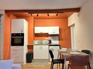 une cuisine avec des murs orange et une table avec des chaises dans l'établissement Le Terracotta, central et intimiste, à La Celle-sous-Gouzon 23 autres photos