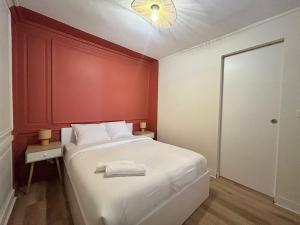 une chambre avec un lit blanc avec un mur rouge dans l'établissement Le Terracotta, central et intimiste, à La Celle-sous-Gouzon
