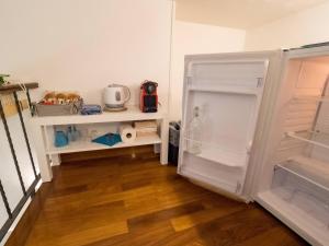 an empty white refrigerator in a kitchen with wooden floors at Picagetta Tiny Room with AC in Vernazza
