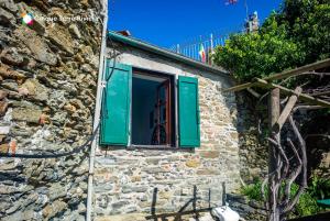 een raam met groene luiken op een stenen gebouw bij Muin a Ventu Historical Tower in Vernazza