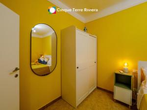 a yellow room with a mirror and a bed at Ca' Bea Apartment with AC and Terrace in Vernazza