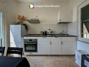a kitchen with white cabinets and a stove top oven at Ca' Bea Apartment with AC and Terrace in Vernazza +24 photos