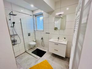 een witte badkamer met douche en wastafel bij Jan Gustav Apartments in Liptovský Mikuláš