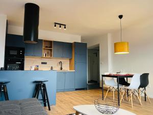 een keuken met blauwe kasten en een tafel en stoelen bij Jan Gustav Apartments in Liptovský Mikuláš +49 foto's