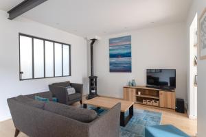 ein Wohnzimmer mit Sofa und Fernseher in der Unterkunft Le Rock Fish - Quelques minutes de la plage in Dinard