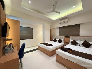 a hotel room with two beds and a flat screen tv at Hotel JK Palace Newly Renovate in Shirdi