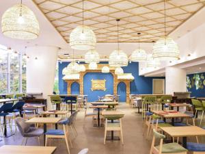 a dining room with tables and chairs and chandeliers at Novotel Bucharest City Centre in Bucharest