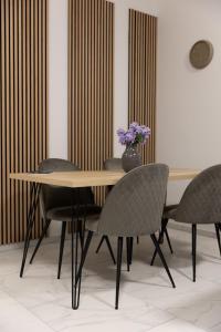 a table with chairs and a vase with purple flowers at Luxury Apartment Brendi in Log pri Brezovici +5 photos