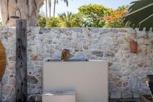 a woman sitting at a counter in front of a stone wall at Wake Up! Byron Bay in Byron Bay