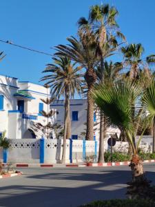 een straat met palmbomen en een wit gebouw bij L'îlot in Sidi Ifni