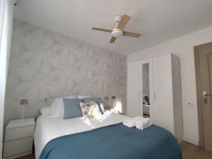 Un dormitorio con una cama con ventilador de techo. en Isla de los Pensamientos, en Faro de Cullera